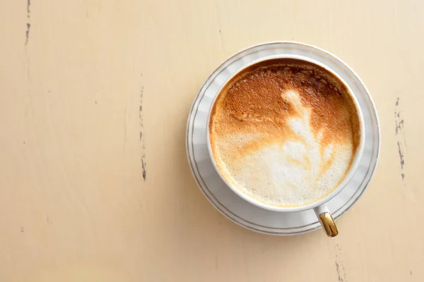 Uma xícara de café com um padrão de folha em uma mesa vintage — Fotografia de Stock