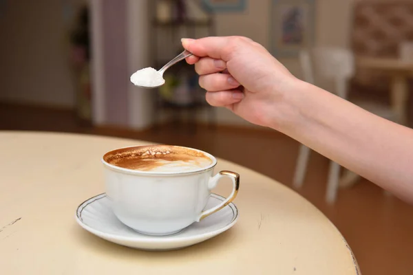 A mão da menina derrama açúcar em seu café — Fotografia de Stock