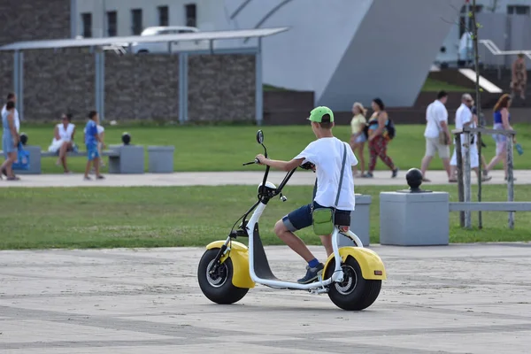 Egy fiatal srác elektromos motorozik nagy kerekekkel. — Stock Fotó