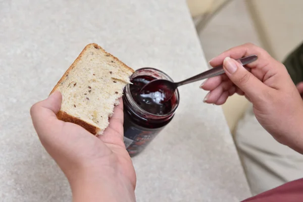 Borůvková marmeláda s lžící na kusu chleba, který leží v ruce — Stock fotografie