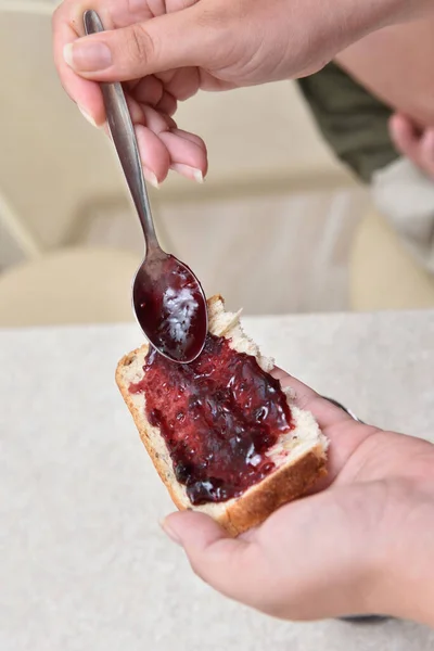 Mermelada de arándanos con una cuchara puesta en un pedazo de pan, que yace en la mano — Foto de Stock
