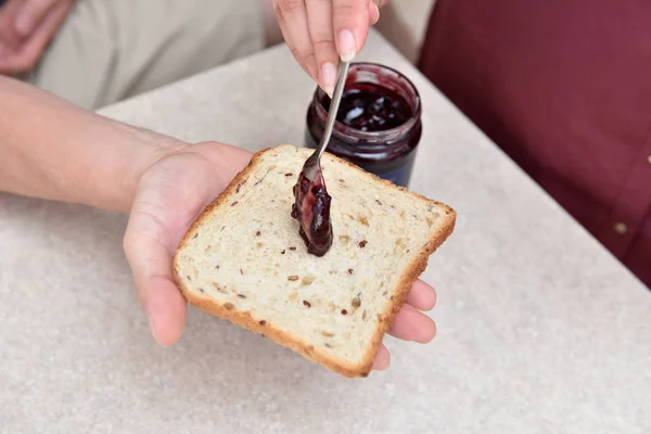 Mermelada de arándanos con una cuchara puesta en un pedazo de pan, que yace en la mano — Foto de Stock