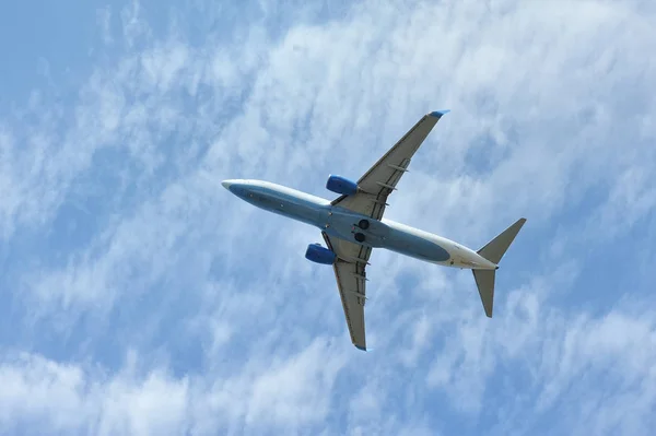 Het passagiersvliegtuig vliegt laag boven op een blauwe hemelse achtergrond. Onderaanzicht — Stockfoto