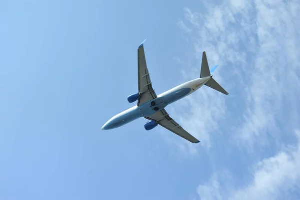 Het passagiersvliegtuig vliegt laag boven op een blauwe hemelse achtergrond. Onderaanzicht — Stockfoto