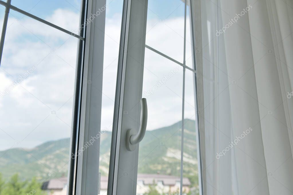 The plastic window is open. Open window with curtains and mountain views