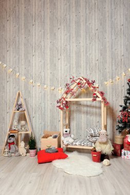 Çocuklar için yeni yıl ya da noel fotoğrafı. Ahşap bir evi, oyuncakları, Noel ağacı ve sıcak bir ışığı olan çocukların fotoğraf bölgesi.