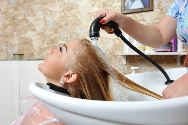 Después de teñir el cabello, la peluquera lava el cabello de la chica y wa — Foto de Stock