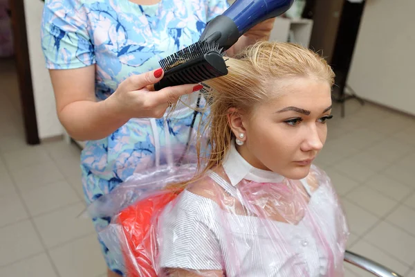 O cabeleireiro seca o cabelo molhado depois de pintar. Loira — Fotografia de Stock