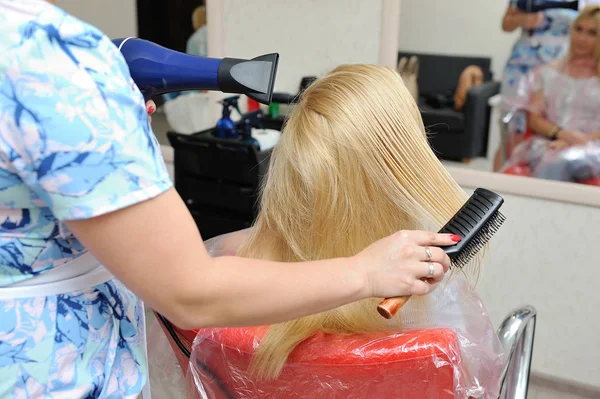 Der Friseur trocknet das nasse Haar nach dem Malen. blond — Stockfoto
