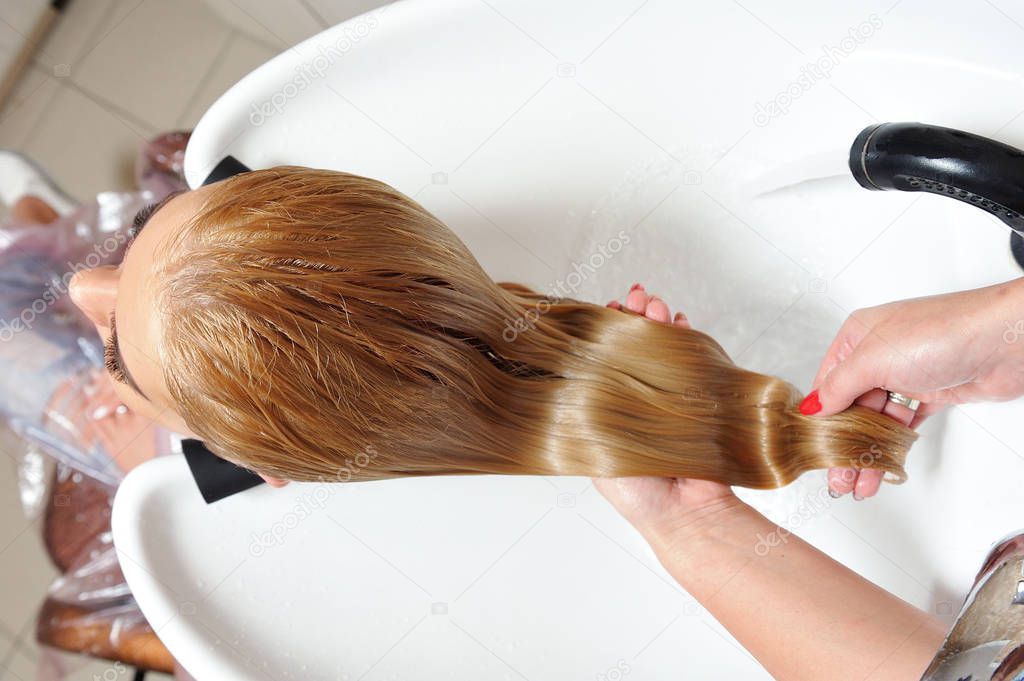 The girl washes her hair in a hairdresser, after painting her hair. Blonde