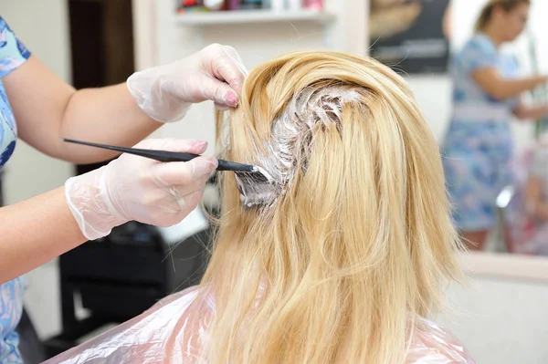 El peluquero utiliza un cepillo para aplicar el tinte en el cabello, para d — Foto de Stock
