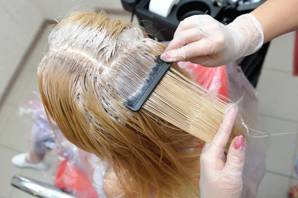 De kapper smeert de verf op zijn haar met een kam, voor co — Stockfoto