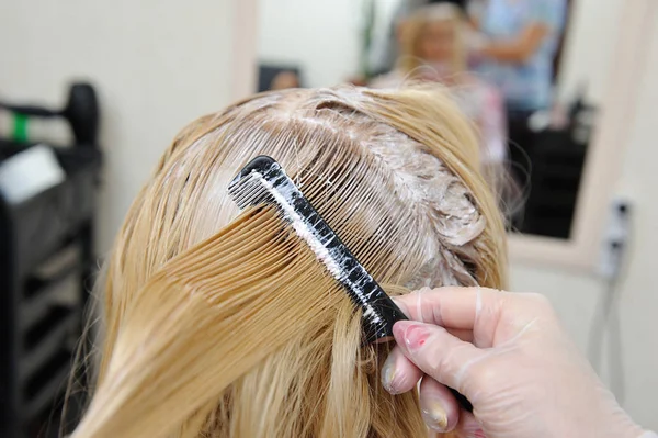 Le coiffeur enduit la peinture sur ses cheveux avec un peigne, pour co — Photo