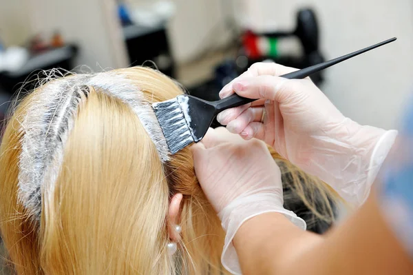 Der Friseur verwendet einen Pinsel, um den Farbstoff auf die Haare aufzutragen, für d Stockbild