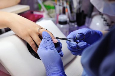 Özel bir makasla manikürcü tırnak derisini yüzüyor.