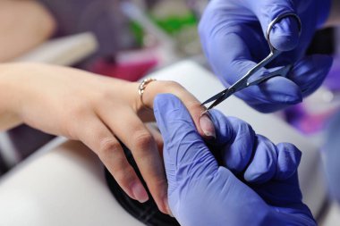 Özel bir makasla manikürcü tırnak derisini yüzüyor.