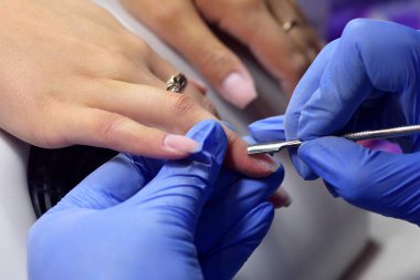 Özel bir aletle manikürcü tırnağındaki fazla deriyi söker., 