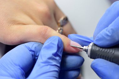 Manikürcü, incelenmeden önce tırnak ve deri yüzeyini cilalar.