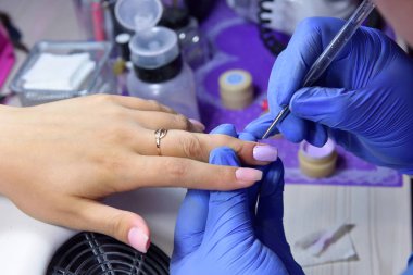 Manikürcü yeni jöleye boya sürmek için çok ince bir fırça kullanıyor. 