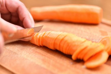 Havuç kesme. Bıçaklı kadın eller kesme tahtasındaki havuçları doğruyor. Yakın plan.