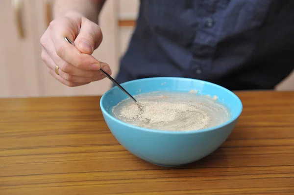 Przygotować ciasto do domowego pieczenia, ręcznie ugniatać suche drożdże w wodzie — Zdjęcie stockowe