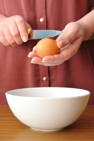 Female hands smash the chicken egg with a knife over a bowl of wheat flour in the kitchen — Stock Photo, Image