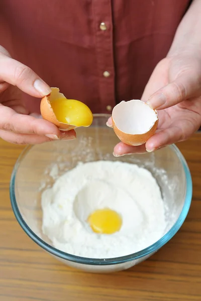 Female hands separate the egg white from the yolk over a bowl of wheat flour in the kitchen — Stock Photo, Image