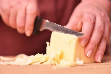 Kadın eli ve bıçak kesme tahtasında taze parmesan peyniri kesiyor. Yakın plan.