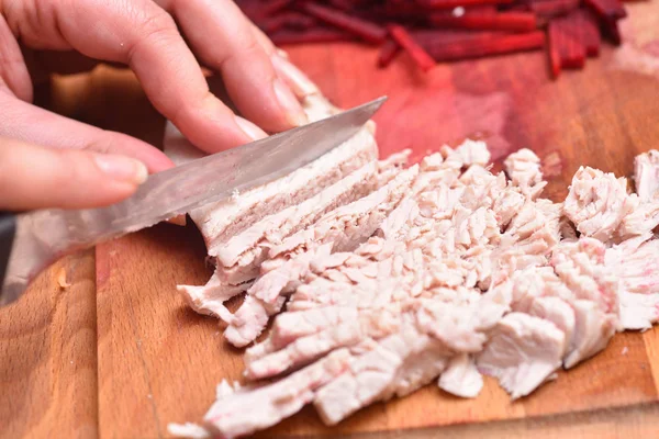 Sliced boiled turkey meat. Female hands with a knife cut boiled turkey meat