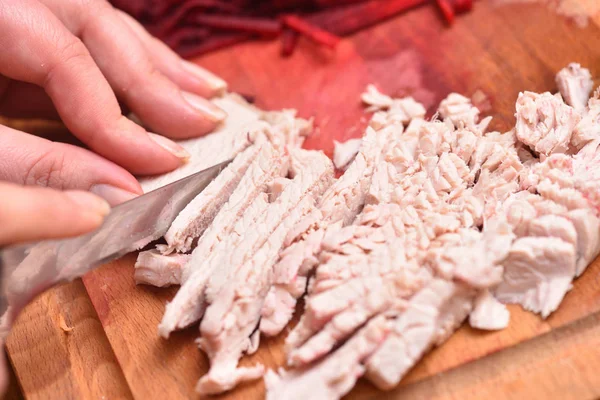Нарезанное вареное мясо индейки. Руки женщины с ножом, отрезанным варёным мясом индейки — стоковое фото