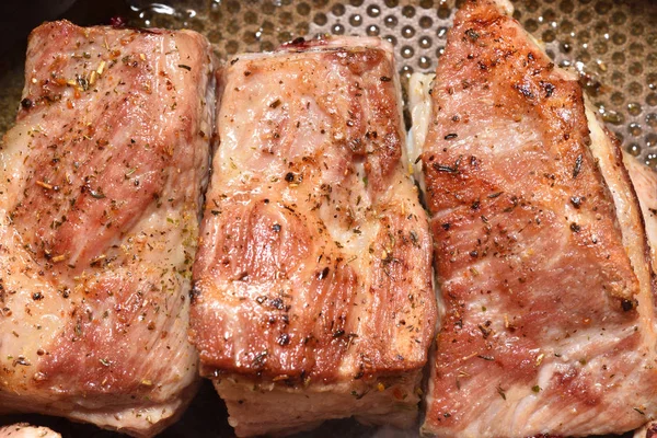 Schöne, rötliche Schweinerippchen werden in einer Pfanne gebraten. Nahaufnahme — Stockfoto