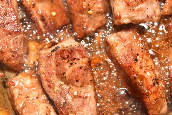 Schöne, rötliche Schweinerippchen werden in einer Pfanne gebraten. Nahaufnahme — Stockfoto