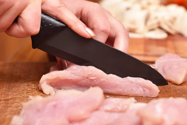 Viande de dinde crue tranchée. Préparation de la viande de dinde pour le dîner de cuisine. Le couteau coupe la viande de dinde. Gros plan — Photo