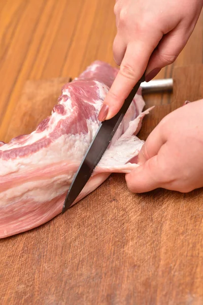 La donna taglia il grasso sulla carne cruda. Tagliare il grasso in eccesso dalla carne di maiale sulle costole. Rimuovere il grasso indesiderato sulla carne — Foto Stock