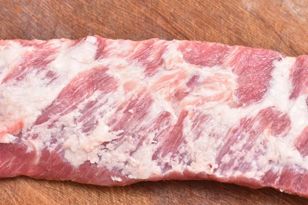 Сырое мясо, свиные ребрышки, необрезанные, на деревянной доске — стоковое фото