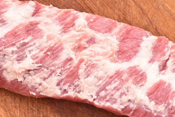 Rohes Fleisch, Schweinerippchen, ungeschnitten, auf einem Holzschneidebrett — Stockfoto