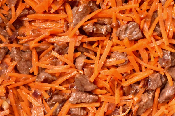 Обжарка овощей и мяса в сковороде с антипригарным покрытием. Лук, морковь и мясо. Крупный план — стоковое фото