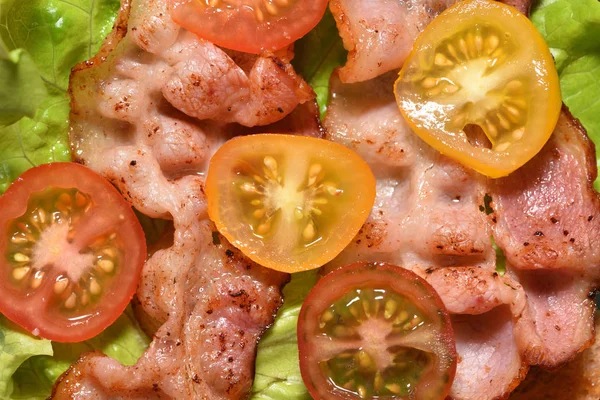 Bacon frito em alface e tomate cereja, para um café da manhã saboroso. Close-up — Fotografia de Stock