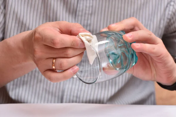 As mãos do homem, usando um guardanapo, limpam um copo transparente para beber para que não haja manchas. Close-up — Fotografia de Stock