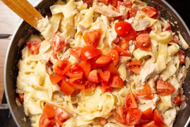 Evde makarna pişirmek. Bir tavaya yapıştır ve kiraz domatesine malzeme ekle. Yakın plan.
