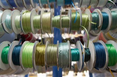 Renkli kurdeleler, mağazanın rafındaki bobinlerde nakış işi için. Yakın plan.