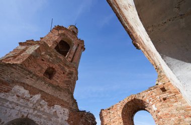 Eski yıkılmış ve terk edilmiş kilise mavi gökyüzüne karşı, tarlanın ortasında.
