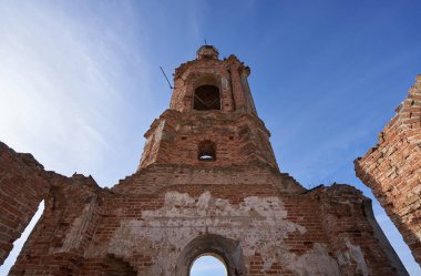 Eski yıkılmış ve terk edilmiş kilise mavi gökyüzüne karşı, tarlanın ortasında.