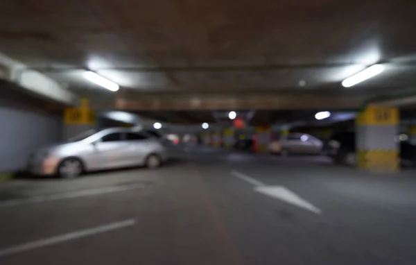 Fondo borroso aparcamiento subterráneo para coches con flechas en el centro comercial. Imagen desenfocada — Foto de Stock