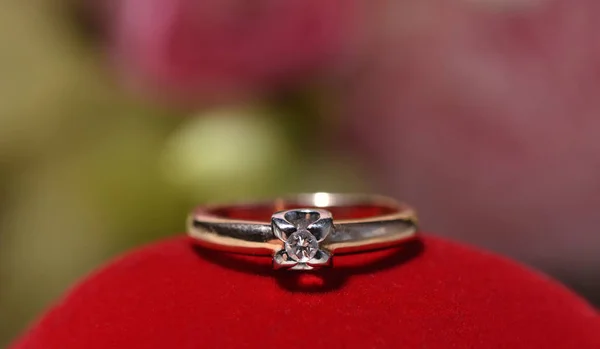 Beautiful engagement ring with a diamond on a red surface. Closeup for template for text.