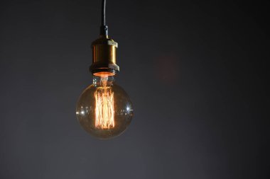 Gri bir duvarın arka planında parlak ipliklerle güzel, yuvarlak bir retro lamba.