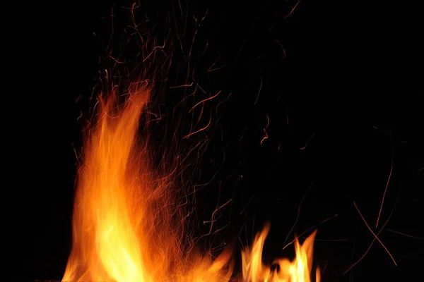 黒を背景に夜に火花と燃える火の炎 — ストック写真