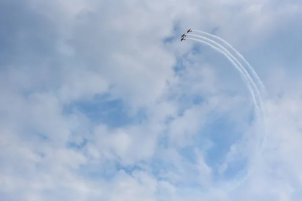 Airshow of the Russian aerobatic team on piston aircraft with propellers against a rainy sky with clouds.