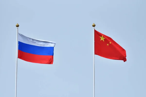 Флаг Китая России Размахивающий Ветру Против Белого Облачно Синего Неба — стоковое фото
