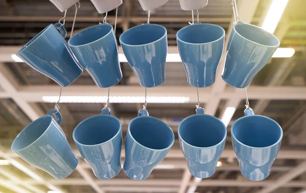 Many blue mugs are hung on the bench in the store.